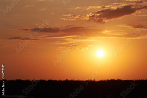 A bright orange sunset in the sky with clouds on the horizon in the evening. Nature and weather forecast