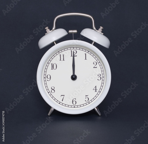 Old-style alarm clock, black and white, it's twelve o'clock.