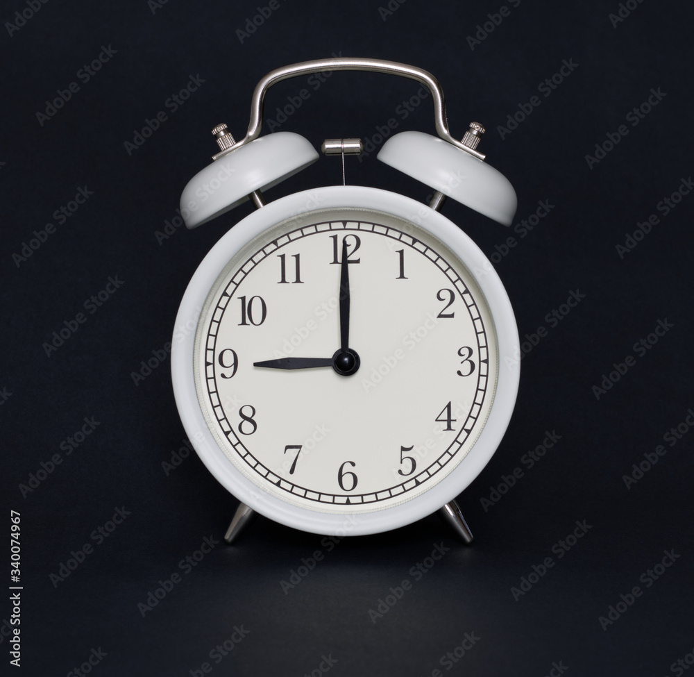 Old-style alarm clock, black and white, it's nine o'clock.