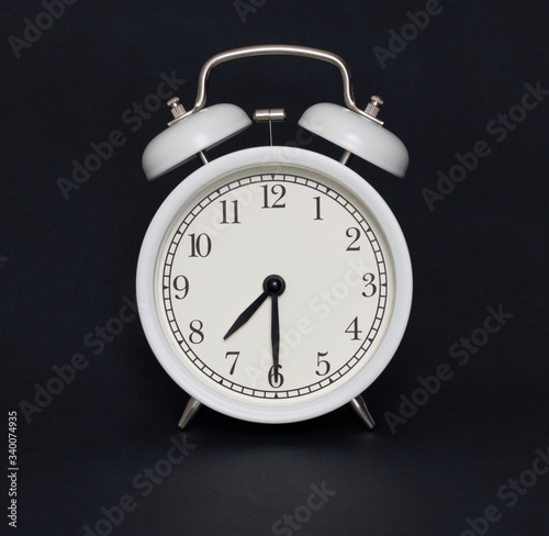 Old-style alarm clock, black and white, it's half past seven.