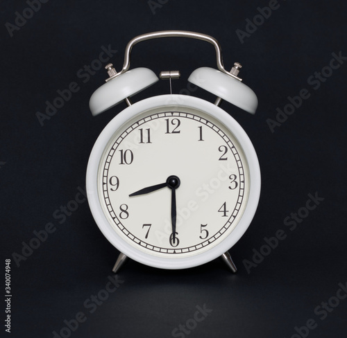 Old-style alarm clock, black and white, it's half past eight.