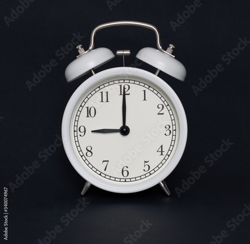 Old-style alarm clock, black and white, it's nine o'clock.