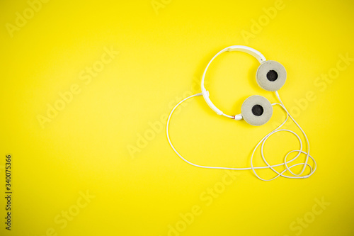 White audio headphones with a 3.5 mm wire on a yellow background 