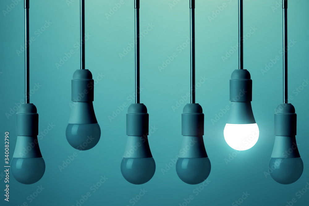 The LED lamp is illuminated and the other bulbs do not glow on a deep blue background. Creativity concept. The LED lamp is illuminated and the other bulbs do not glow on a deep blue background. Creativity concept.