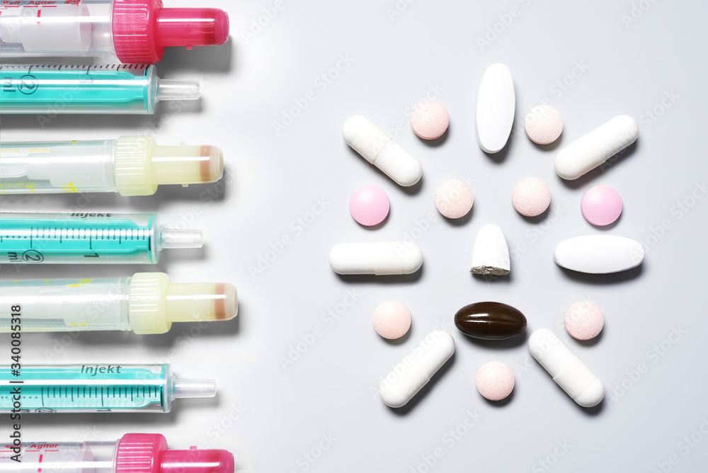 Empty syringes without needles aimed at “coronavirus face” made of pills and capsules Empty syringes without needles aimed at “coronavirus face” made of pills and capsules
