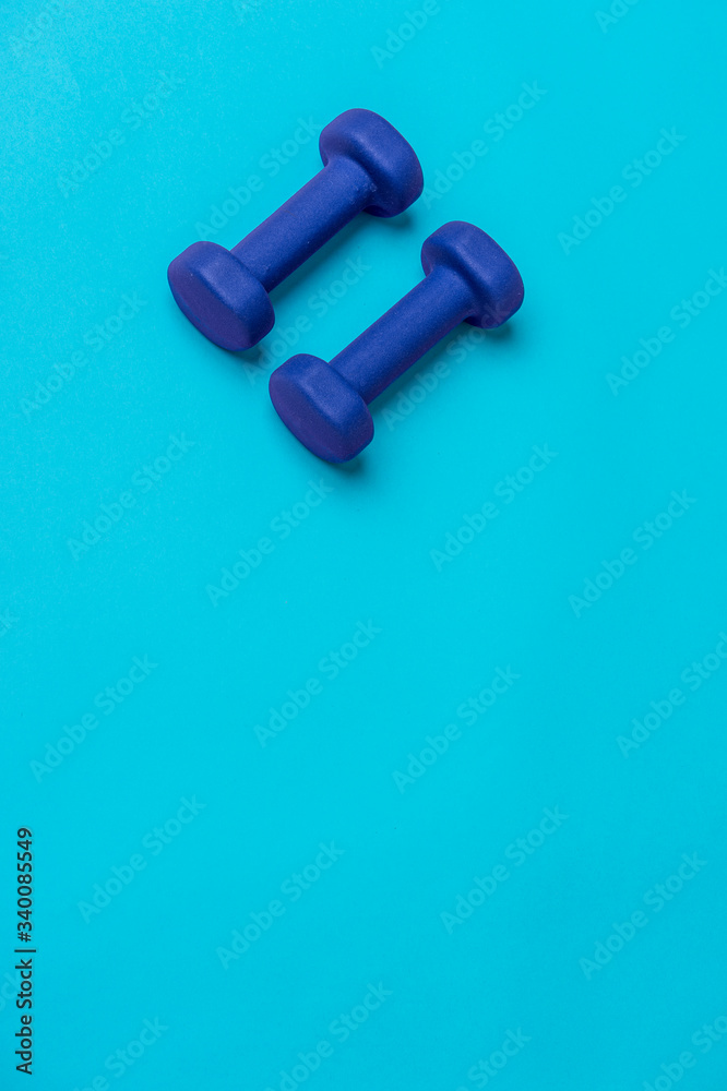 Two dumbbells of blue color isolated on a light blue background. Healthy lifestyle concept. Two dumbbells of blue color isolated on a light blue background. Healthy lifestyle concept.