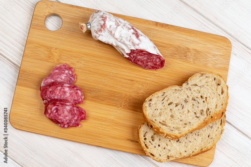 Sliced cereal bread and slices of dried Italian flask on a wooden cutting board. Simple food for a snack at home Sliced cereal bread and slices of dried Italian flask on a wooden cutting board. Simple food for a snack at home