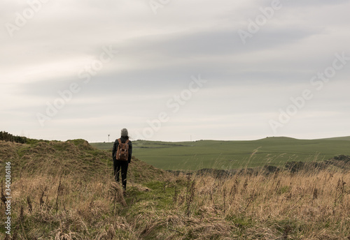 Unrecognizable girl from behind with a backpack in a field