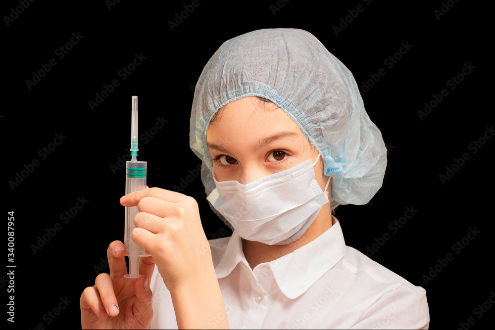 Young woman doctor nurse wearing medical mask and hat, holding empty syringe on black background. Vaccine, immunization and protection from coronavirus infection, health care concept