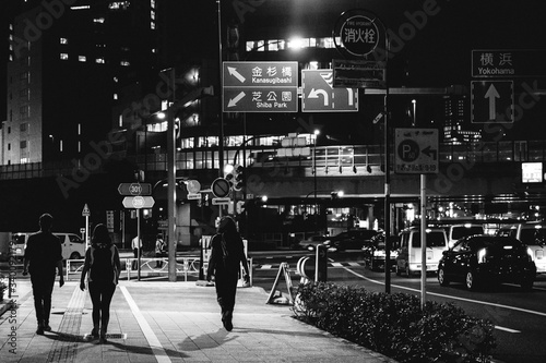 Traffic, lights, signs and backpackers walking at Tokyo Downtown by night, japan (in black and white)