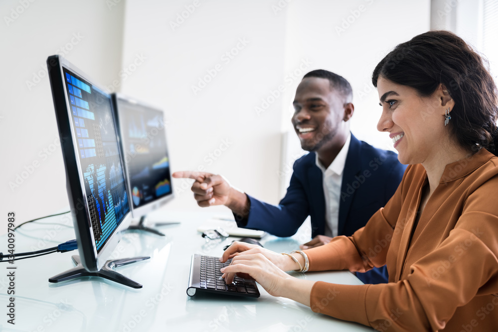 Two Businesspeople Examining Graph On Computer Two Businesspeople Examining Graph On Computer