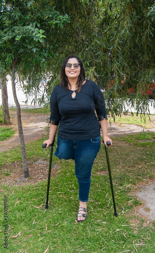 Young beautiful amputee woman walking with crutches photo