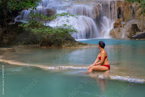 Woman in red bikini look water at Erawan Waterfall and natural