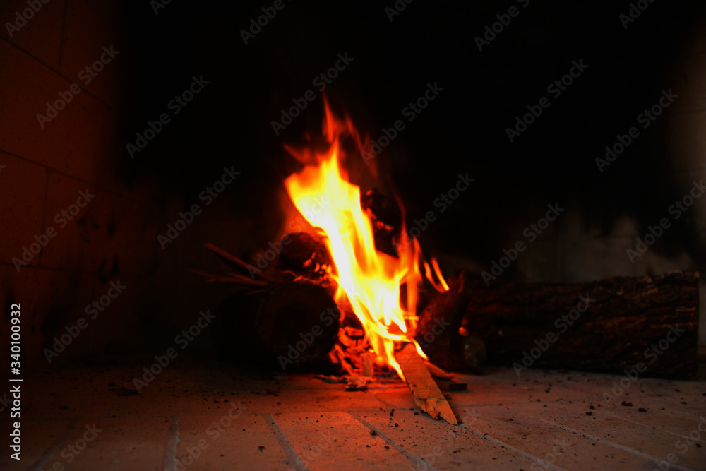 Fire burning between the wood of the fireplace lighting the house