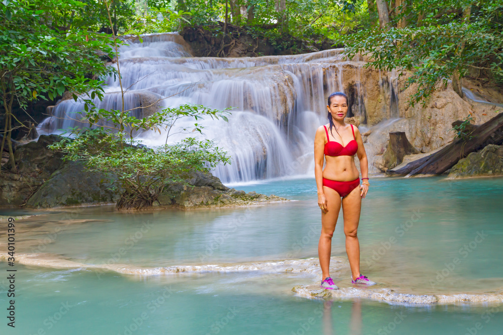 Woman beautiful in red bikini at Erawan Waterfall and natural