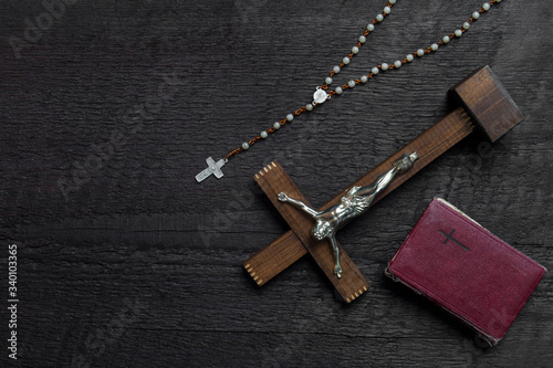 Christian cross on wood bible and rosary beads over wooden vintage background