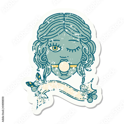 grunge sticker with banner of winking female face with ball gag