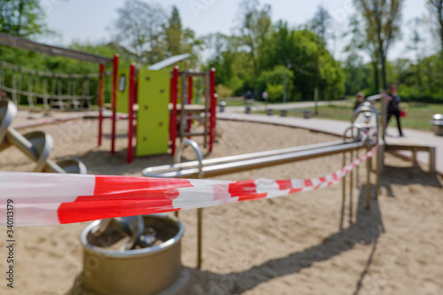 Close up view,Red and white alarm caution tape wrapped around closed outdoor playground toys during global quarantine from COVID-19. Lockdown  and quarantine time in epidemic of COVID-19 Virus crisis.
