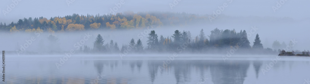 morning mist over lake with island in autumn colour Algonquin park Ontario Canada