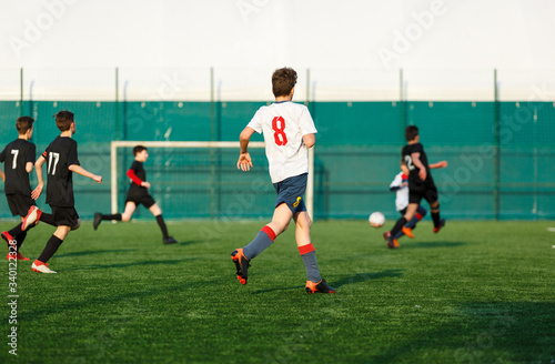 Boys in  white black sportswear running on soccer field. Young footballers dribble and kick football ball in game. Training, active lifestyle, sport, children activity concept © Natali