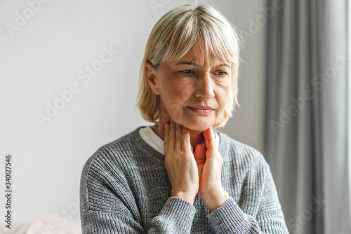 Sick senior adult elderly women touching the neck feeling unwell coughing with sore throat pain.Healthcare and medicine concept