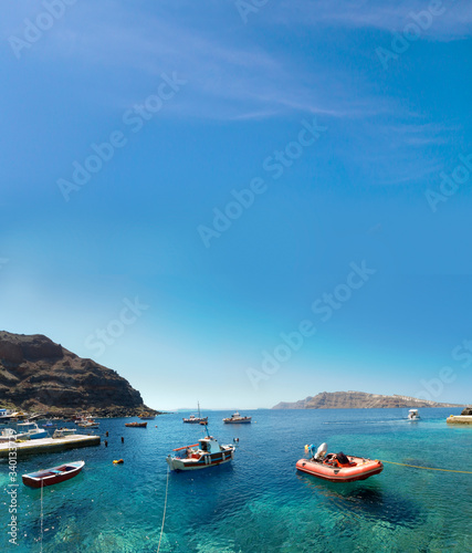 boats at the fishing harbour village of Oia and Amoudi Bay in Santorini greek island clear meditoraiian clear blue waters and sky