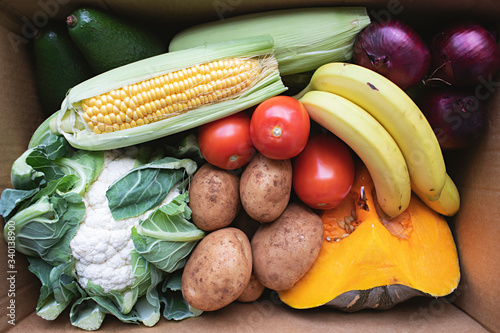 A box of fresh fruit and vegetables is left at a front door photo