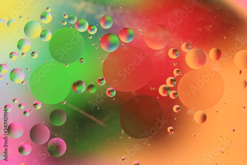 macro of oil mixed with water on colorful red, yellow, pink, green, blue background, colourful circles, copy space, vertical