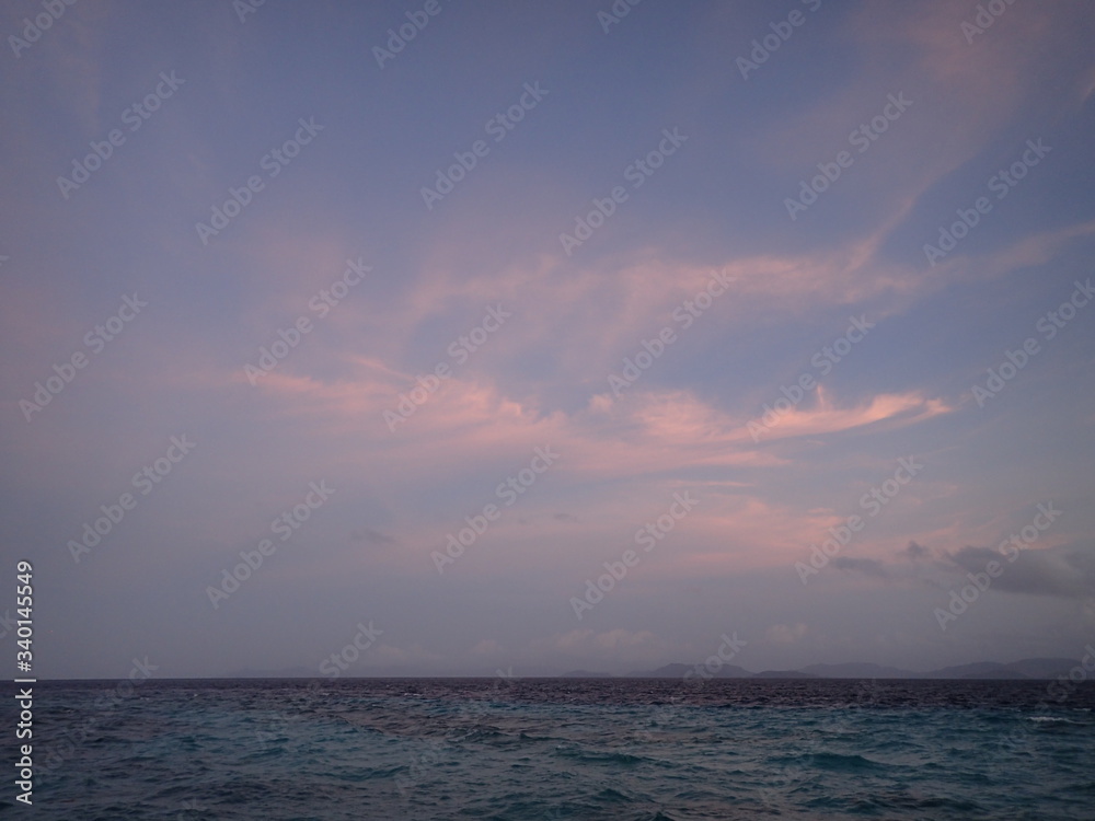 水平線の朝焼けのピンク色の雲
