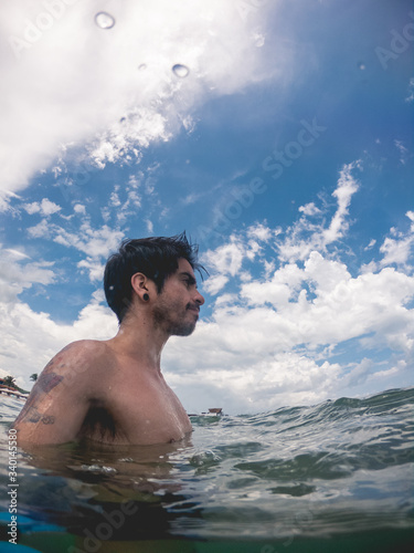 Selfie of  young and fit man with tattooed arms swimming at the green and calypso ocean with cloudy blue sky, Riviera Maya coast, Mexico © Samuel Ponce