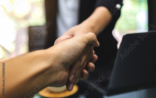 Closeup image of two businesspeople shaking hands in office