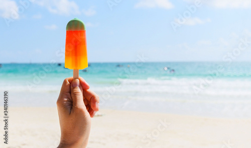 Ice cream stick in hand with sea background - Colorful ice cream fruit on beach in summer hot weather ocean landscape nature outdoor vacation
