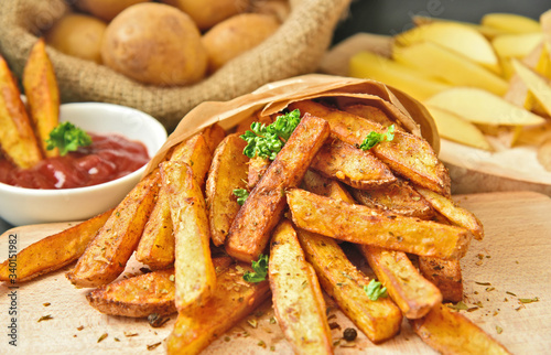 Homemade Crispy Seasoned French Fries..French fries  with spicy seasoning in brown paper bag on wooden broad.