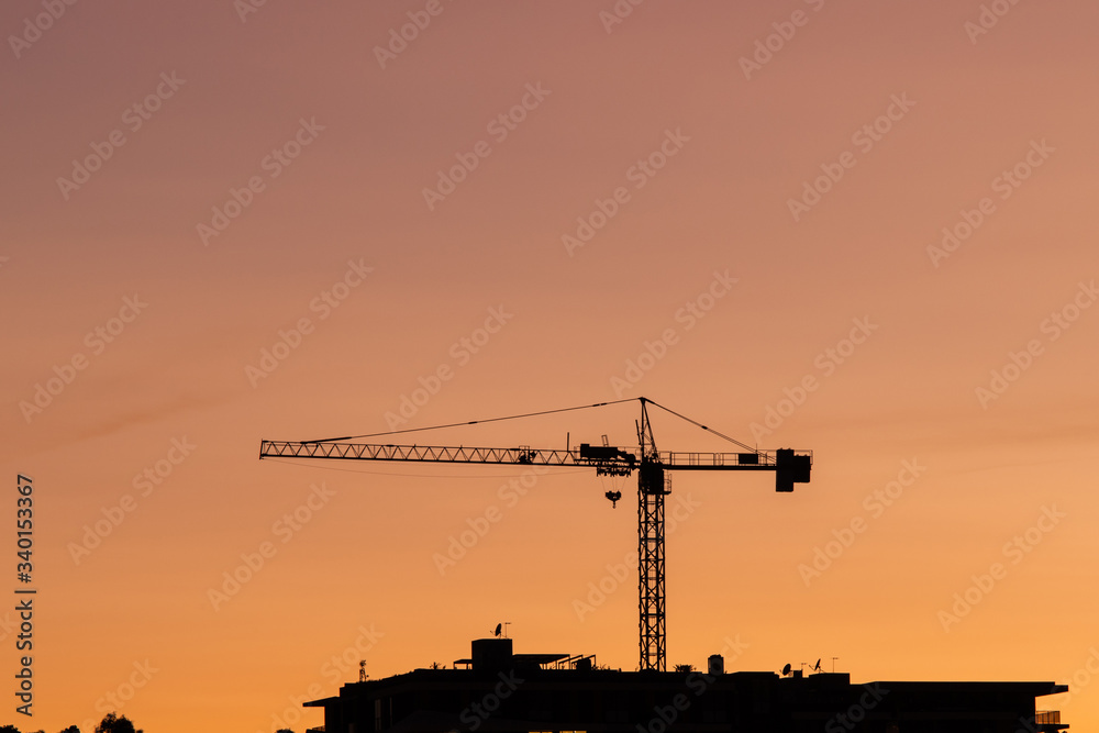 Silhouette of crane with orange sky.