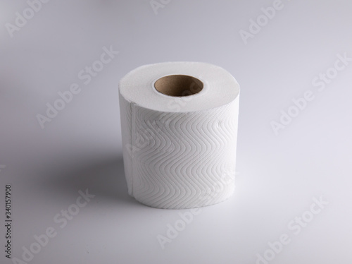 The unused white tissue roll was taken in a studio shot on a white background, with detailed details on the surface, the waves and perforations looking soft and providing comfort to users.