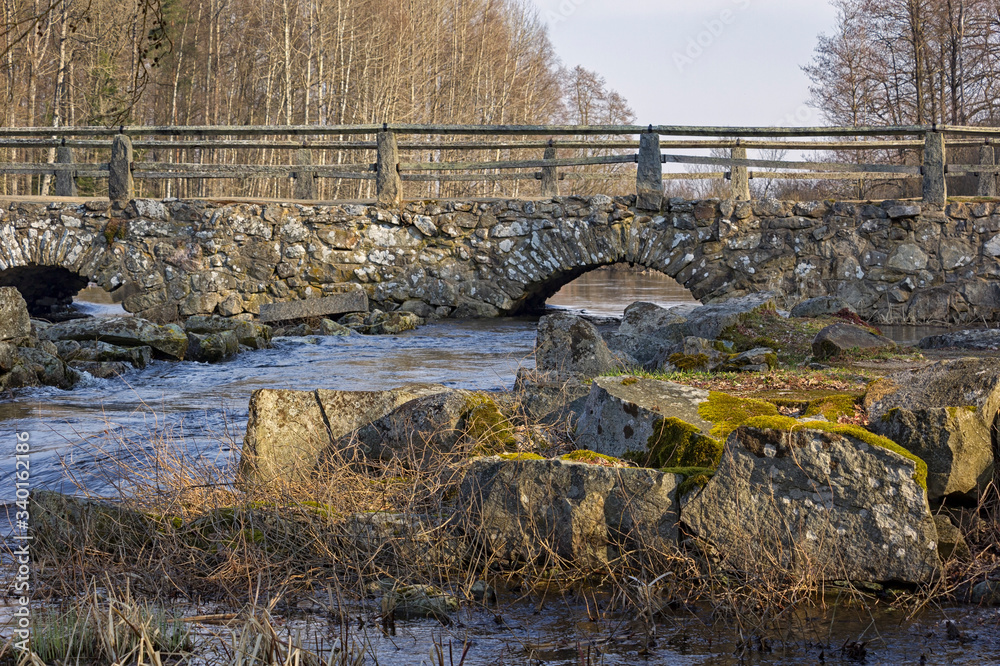 View of an old, historic stone bridge over a small river in the south of Sweden.