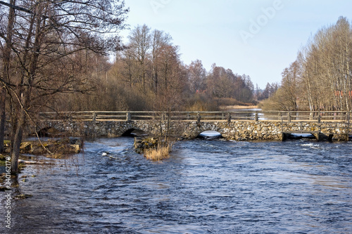 View of an old, historic stone bridge over a small river in the south of Sweden.