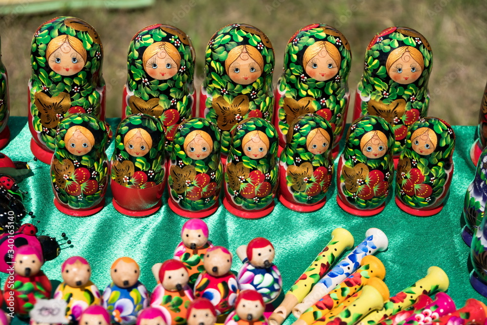 Bright souvenir traditional Matryoshka dolls of handmade stand together on the table with other wooden toys.