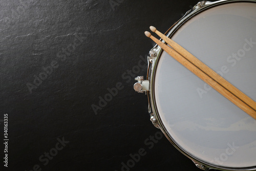 Leinwand Poster Drum stick and drum on black table background, top view, music concept