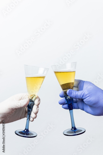 human hands with protective gloves toast with two cups. Concept of the end of the coronavirus crisis, covid 19