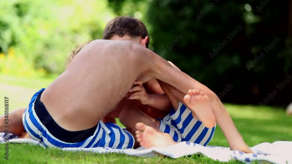 Two brothers fighting each other outside in sunlight. Siblings quarrelling one another