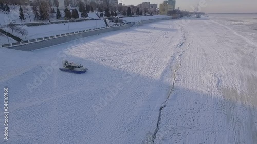 air-cushion vehicle is moving over frozen river in winter day, aerial view
