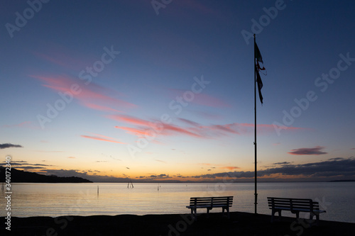 Dusk at Trasimeno lake (Umbria, Italy), with a parking bench and a worn flag on the foreground © Massimo