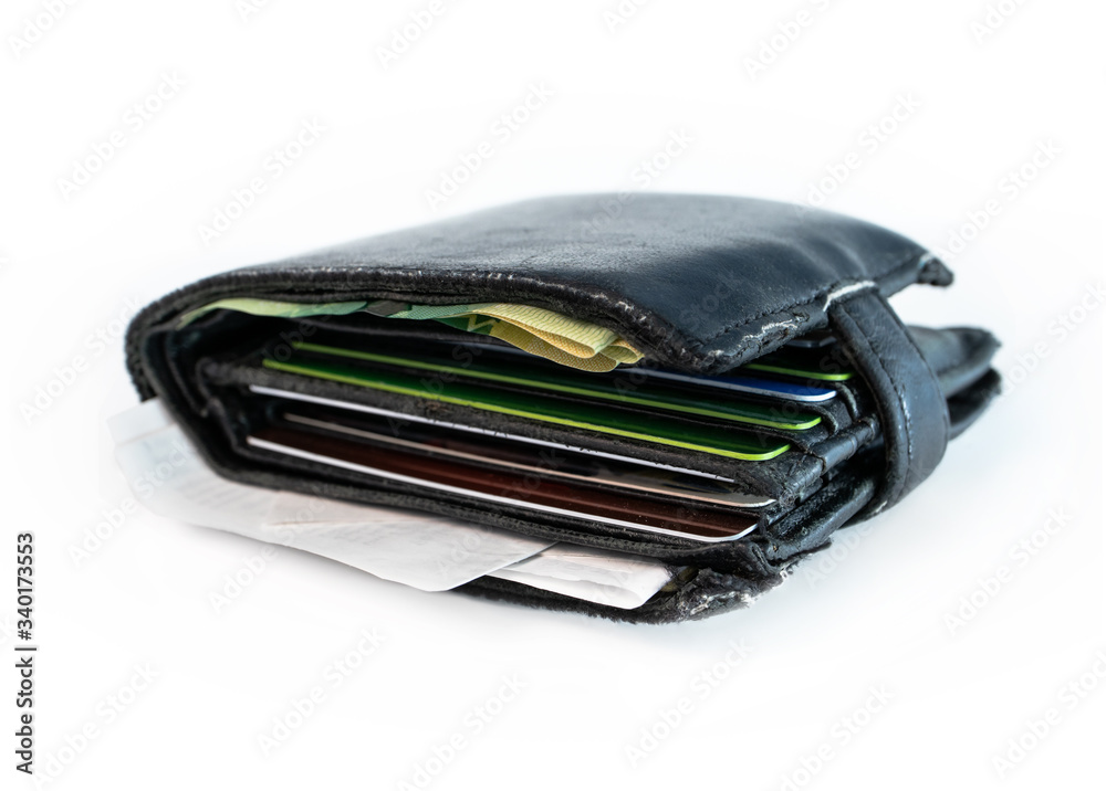 Worn out and full wallet, portemonnaie or money purse. Close up. Black leather. Some bills, receipts and several debit cards, credit cards or gift cards visible. Isolated on white.
