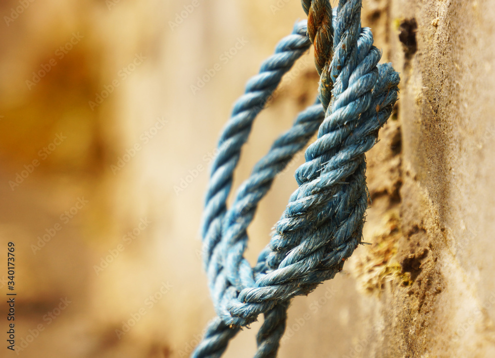A blue rope hangs on a concrete slab. There is room for text       