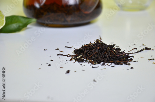 Transparent teapot with black tea, dry tea brewing on the table, bergamot slices, or lemon or lime on a white background