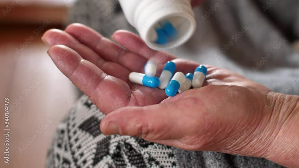 hand Senior adult woman pills a pill from a bottle Into her hand. Painkiller pills on a female hand from a bottle of medicine. concept: Pharmaceutical medicine, medicine in containers for health. trea hand Senior adult woman pills a pill from a bottle Into her hand. Painkiller pills on a female hand from a bottle of medicine. concept: Pharmaceutical medicine, medicine in containers for health. trea