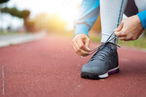 Sporty woman ties her shoes before jogging