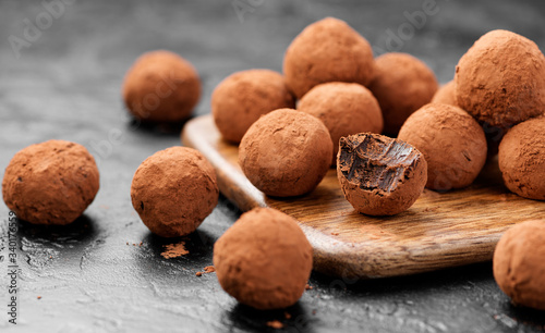 Handmade chocolate truffles covered with cocoa on black background.