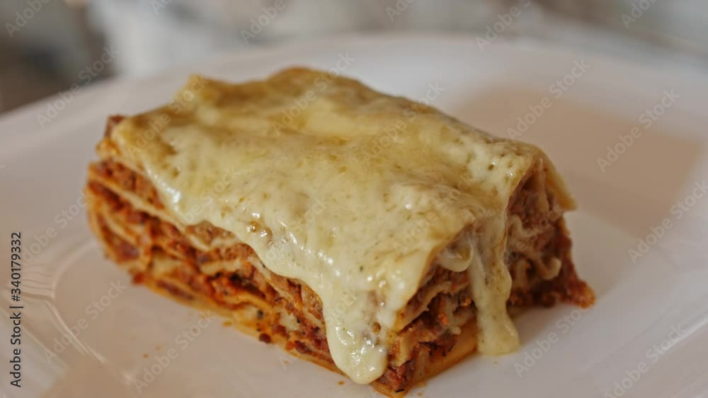 Italian food. Close-up shot of meat lasagna on a white plate. Slow motion. Italian food. Close-up shot of meat lasagna on a white plate. Slow motion.